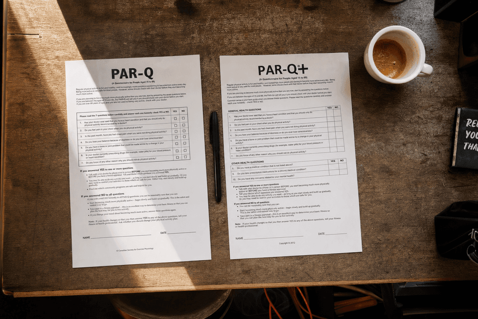A printed PAR-Q and PAR-Q+ questionnaire side by side on a wooden desk