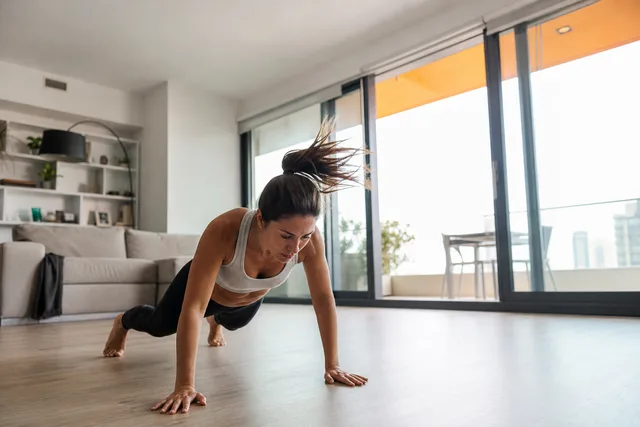 A woman doing a burpee at home