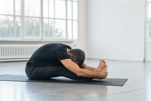 A man holding a seated forward-fold stretch