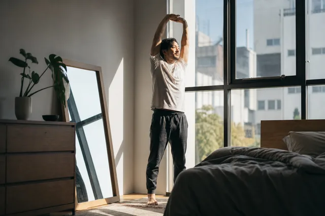 A man stretching by a sunlit window
